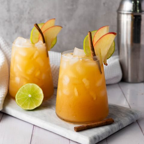 image shows two apple cider mocktails on the counter