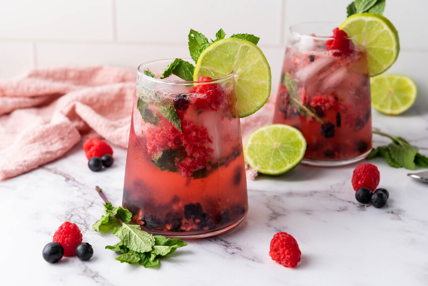 image shows two summer berry mocktails on a counter