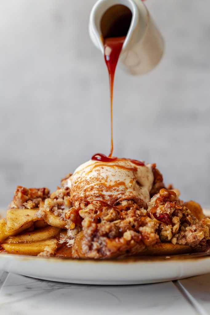 pouring caramel sauce on apple crisp