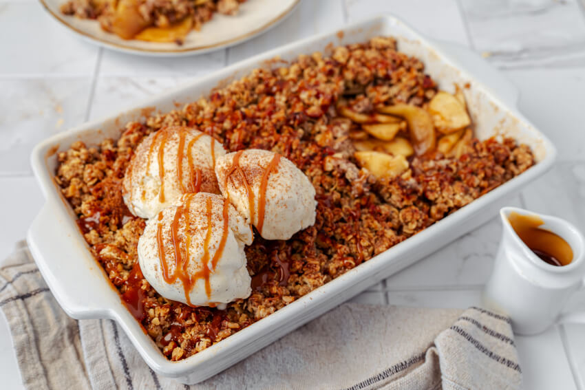 image shows cooked apple crisp with vanilla ice cream and caramel syrup
